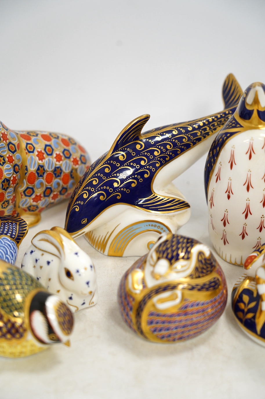 Eight Royal Crown Derby porcelain paperweights in the form of animals including a penguin, rabbit and seal, largest 17cm wide. Condition - seven good, one broken